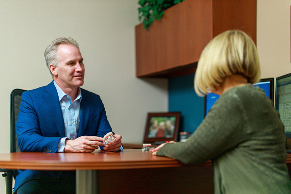Dr. Scherer speaking to patient at desk at Wheaton Oral Surgery in Naperville, IL