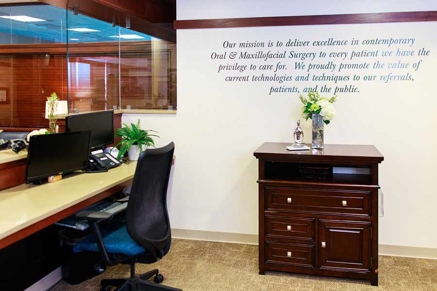 Desk area with mission statement on wall at Wheaton Oral Surgery in Naperville, IL