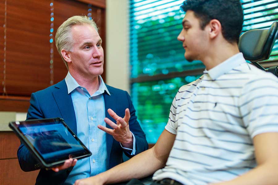 Dr. Scherer holding digital tablet to patient at Wheaton Oral Surgery in Naperville, IL