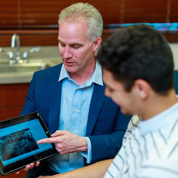 Dr. Scherer and patient, holding digital tablet with x-ray at Wheaton Oral Surgery in Naperville, IL