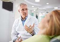 Dentist talking with reclining patient