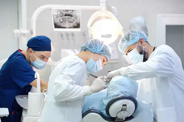 A team of dentists and oral surgeons performing a dental procedure on a patient in a well-equipped surgical setting.